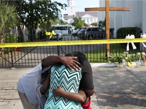People mourn together in front of the Emanuel African Methodist Episcopal Church after a mass shooting at the church that killed nine people of June 19, 2015.