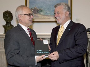 Quebec Premier Philippe Couillard, right, present a copy of the provincial budget by Finance Minister Carlos Leitão, in 2014 that changed the rules regarding pension splitting for Quebecers under the age of 65.