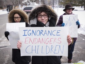 Pro-sex education demonstrators hold signs in opposition to a protest opposing Ontario's new sex education curriculum in front of Queen's Park in Toronto on Tuesday, February 24, 2015.