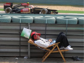 A track marshal sleeps as Lotus driver Kimi Raikkonen of Finland (background) drives past during a 2013 practice session of the Formula One Chinese Grand Prix.