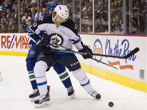 VANCOUVER, BC - MARCH 24: Michael Frolik #67 of the Winnipeg Jets tries to fight off the check of Dan Hamhuis #2 of the Vancouver Canucks in NHL action on March, 24, 2015 at Rogers Arena in Vancouver, British Columbia, Canada.