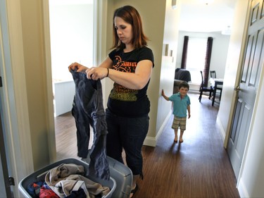 Julie Pare with son Zackary watching, unpacks clothes in the new apartment they recently moved into in the town of Lac-Mgantic, Friday July 03, 2015.  The building was provided to families in need following the 2013 train derailment and subsequent fire that destroyed the centre of the town and killed 47 people.  Pare, mother of 3 children, has moved 4 times in the last two years because of the disaster.