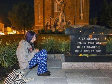 Karol-Ann Picard-Beauvais sits next to the memorial outside Paroisse Ste-Agnes in Lac-Megantic, 250 kilometres east of Montreal Monday July 06, 2015 at 1:15 in the morning, the same time as the 2013 train derailment and explosion that levelled the centre of the town, killing 47 people.