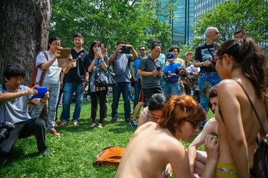 MONTREAL, QUE.: JULY 5, 2015 -- Tourists take photos as participants gather to take part in the Montreal World Naked Bike Ride at Dorchester Square in downtown Montreal on Sunday, July 5, 2015.  The World Naked Bike Ride event aims to encourage cycling, promote environmentalism, and address body image issues. (Dario Ayala / Montreal Gazette)