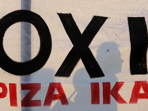 A demonstrator stands behind a banner reading ''NO'' during an anti-austerity rally in Athens, Friday, June 10, 2015. Greek Prime Minister Alexis Tsipras sought his left-wing party's backing on Friday for a new budget austerity package that is harsher than what he urged Greeks to reject in a vote just last week, but would provide the country will longer-term financial support.