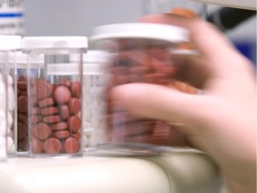 A pharmacist pours pills removes pills from a counter at a Jean Coutu pharmacy in downtown Montreal.