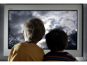 Two young child watch television at home.