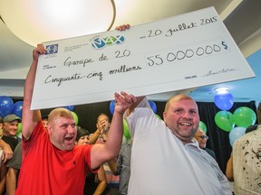 Two of Lotto Max's $55 million jackpot winners Eric Valois, left, and colleague Carl Brunelle, right, pose for a photo with the big cheque. The amount will be split between the 20 colleagues.