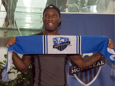 Montreal Impact's newest player Didier Drogba holds up a team scarf as he arrives at Trudeau airport, Wednesday, July 29, 2015 in Montreal.