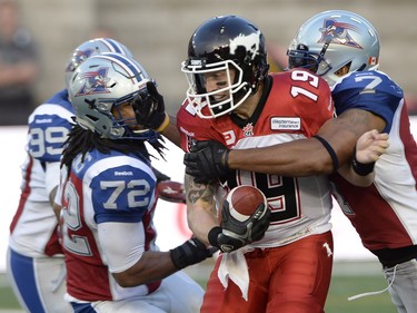 Calgary Stampeders quarterback Bo Levi Mitchell (19) is sacked by Montreal Alouettes' Darrin Kitchens (72) and John Bowman (7) during first half CFL football action in Montreal, Friday July 3, 2015. THE CANADIAN PRESS/Ryan Remiorz