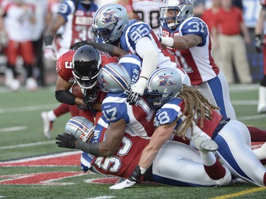 Calgary Stampeders' Jon Cornish (9) is stopped after making the first down by Montreal Alouettes' Gabriel Knapton (55), Billy Parker (17), Bear Woods (48), Corvey Irvin (95) and Winston Venable (31) during first half CFL football action in Montreal, Friday July 3, 2015. THE CANADIAN PRESS/Ryan Remiorz