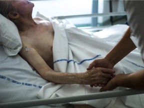 A file picture shows a nurse holding the hand of an elderly patient in  a palliative care unit.