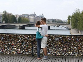 A couple kisses in front of the  Pont des Arts on August 30, 2013 in Paris. Thousands of "love locks" have been attached to this bridge since 2008, and the phenomenon has recently come to Montreal.