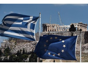 An EU and a Greek flag wave in front of the Parthenon atop the Acropolis hill in Athens on July 7, 2015.