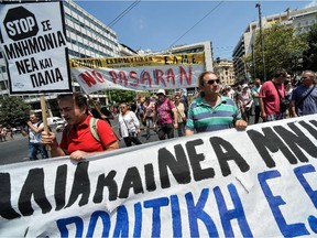 Protestors hold a banner during a protest march in central Athens on July 15, 2015 marking a 24-hour public sector worker and pharmacists strike against the new package of austerity measures.