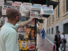 A man reads newspapers' headlines in Athens on July 1, 2015. Nearly one in two Greeks intend to vote 'No' in a weekend referendum on the terms of its bailout, but capital controls are boosting the 'Yes' camp, a poll showed today. Prime Minister Alexis Tsipras has called on Greeks to vote 'No' in the plebiscite, which will ask voters whether they want to accept the latest deal from Athens' creditors — a deal he has branded "humiliating."