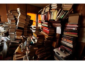 Books sit stacked in a bedroom at a hoarders home.