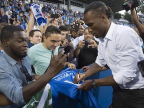 New Impact player Didier Drogba signs a fan's jersey following a news conference at Montreal's Saputo Stadium on July 30, 2015.