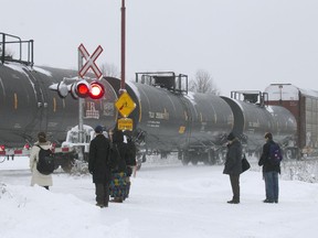 Passengers wait for a freight train to pass before crossing the tracks at the AMT station in Baie d'Urfé.