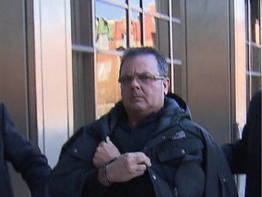 Raynald Desjardins being escorted into SQ headquarters in  December of 2011.