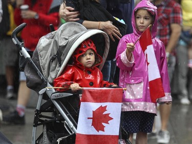 Sisters Sarah, right, and Rory Adam wave flags during Canada Day parade on Ste-Catherine St. in Montreal Wednesday July 1, 2015.