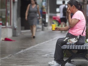 An aboriginal woman holds a cup to gather change from pedestrians, on Ste- Catherine St. near St- Marc  on Tuesday July 07, 2015. A disproportionate number of Montreal's homeless are aboriginal people, according to the census results released Tuesday.