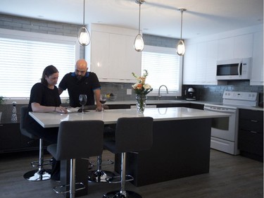 Erin Lefler and  Octavio Mateus leaf through a book while sitting at the extended island in their kitchen.