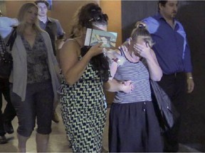 Vanessa Higgins hides her face with her hand as she is surrounded by family and friends at the courthouse in Montreal Tuesday July 14, 2015 for the court appearance of Nicholas Fontanelli.