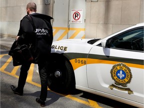 An investigator with Quebec's permanent anti-corruption squad (UPAC) arrives at the offices of engineering firm Dessau Inc. in Montreal on Wednesday July 15, 2015.  The raid was part of an ongoing probe into the city of Montreal's canceled $355.8-million water-management contract.