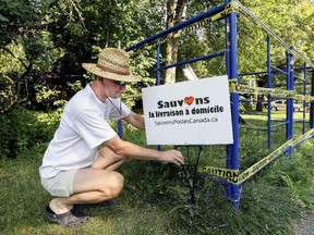 Hans Dybka adjusts the sign on his lawn next to the scaffolding surrounding a load of earth he had dumped on his lawn in Dorval.  He put the earth there after being informed that Canada Post was going to put a community mailbox in front of his property.