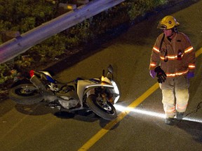 A firefighter walks past a motorcycle that was involved in a fatal accident on Highway 132 early Wednesday, July 22, 2015. Two people died in the accident.