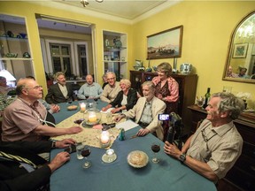 David, second from right, and Diana Nicholson, standing behind him, listen to their guests on Wednesday, July 22, during the weekly salon discussion night they host at their Montreal home.