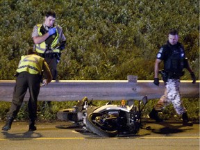 Police inspect a motorcycle that was involved in a fatal accident on Highway 132 near Highway 20 south of Montreal, early Wednesday, July 22, 2015. Two people died in the accident.