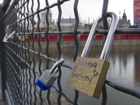 A set of locks with love notes written on them, hang on a fence at a walk bridge over the Bonsecours Basin in Old Montreal, Friday, July 24, 2015.