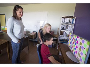 Nathalie Blais left, watches as her son Jake uses a computer to exercise his brain, as Michelle Vaudrin  of Vaudrin Academy, in Vaudreuil- Dorion instructs.