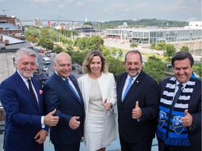 File photo: Left to right: Gilbert Rozon, Transport Minister Robert Poëti, France Chrétien Desmarais, Denis Lebel, then the federal minister of infrastructure and Montreal Mayor Denis Coderre give the thumbs up after announcing a project to illuminate the Jacques-Cartier bridge, seen in the background, in Montreal on July 30, 2015.
