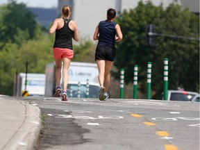 Two joggers run in the oncoming bike lane of the de Maisonneuve street bike path in Montreal on Wednesday July 8, 2015.