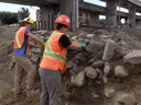 Construction continues  while Quebec archaeologists at the far right are searching an area about the size of a football field at the corner of St-Jacques and St-Rémi Streets in Montreal, on Friday, July 31.