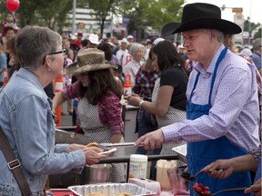 Prime Minister Stephen Harper, right, serves up pancakes and conversation during a Stampede breakfast in Calgary, Alberta on Saturday, July 4 , 2015.