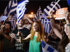 People celebrate in Athens after the first exit-polls of the Greek referendum. Over 60 per cent of Greeks rejected further austerity dictated by the country's EU-IMF creditors in a referendum.