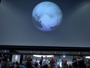 People look at an early image of Pluto taken by NASA's New Horizons probe as the craft makes its closest fly-by of the dwarf planet at the Johns Hopkins University Applied Physics Laboratory July 14, 2015 in Laurel, Maryland. The unmanned NASA spacecraft whizzed by Pluto on JUly 14, making its closest approach in the climax of a decade-long journey to explore the dwarf planet for the first time, the US space agency said. Moving faster than any spacecraft ever built -- at a speed of about 30,800 miles per hour (49,570 kph) -- the flyby happened at 7:49 am (1149 GMT), with the probe running on auto-pilot. It was to pass by Pluto at a distance of 7,767 miles (12,500 kilometers).