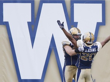 Winnipeg Blue Bombers' Johnny Adams (20) celebrates his interception touchdown with Greg Peach (90) against the Montreal Alouettes during the first half of CFL action in Winnipeg Friday, July 10, 2015.