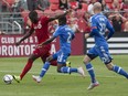 Toronto FC 's Jozy Altidore (left) shoots as from Montreal Impact's Ambroise Oyongo (centre) and Laurent Ciman defend during second half MLS action in Toronto on Saturday August 29, 2015. THE CANADIAN PRESS/Chris Young