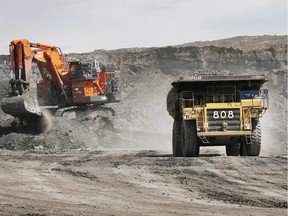 A haul truck carrying a full load drives away from a mining shovel at the Shell Albian Sands oilsands mine near Fort McMurray, Alta.