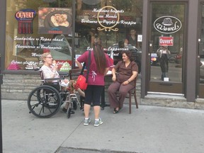 A woman in a wheelchair eats ice cream outside a bakery on St-Laurent Blvd. during the summer of 2014. The shop was given a fine of $250 for "illegal furniture occupying the public domain" after the store set up a table outside for her.