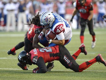 Montreal Alouettes Jean?Christophe Beaulieu (46) is taken down by Ottawa Redblacks Brandon McDonald (22) and Abdul Kanneh (14) during the first half of a CFL game in Ottawa on Friday, Aug. 7, 2015.
