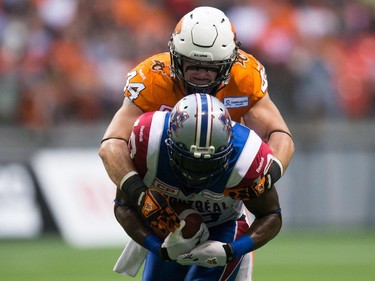B.C. Lions' Adam Bighill, top, jumps on top of Montreal Alouettes' S.J. Green during the first half of a CFL football game in Vancouver, B.C., on Thursday August 20, 2015.
