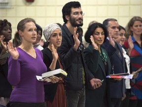 New Canadians take the oath of citizenship at a ceremony in Dartmouth on Tuesday, October 14, 2014.The federal government says Canada welcomed a record number of new citizens in 2014.Citizenship and Immigration Minister Chris Alexander says more than 260,000 people became new Canadians during 2014.