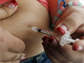 A teenageer with diabetes gives herself an injection of insulin.