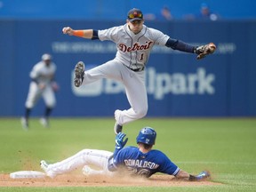 Toronto Blue Jays' Josh Donaldson, bottom, slides safely under a leaping Detroit Tigers' Jose Iglesias following a RBI single during sixth inning MLB baseball action in Toronto on Saturday, August 29, 2015.
